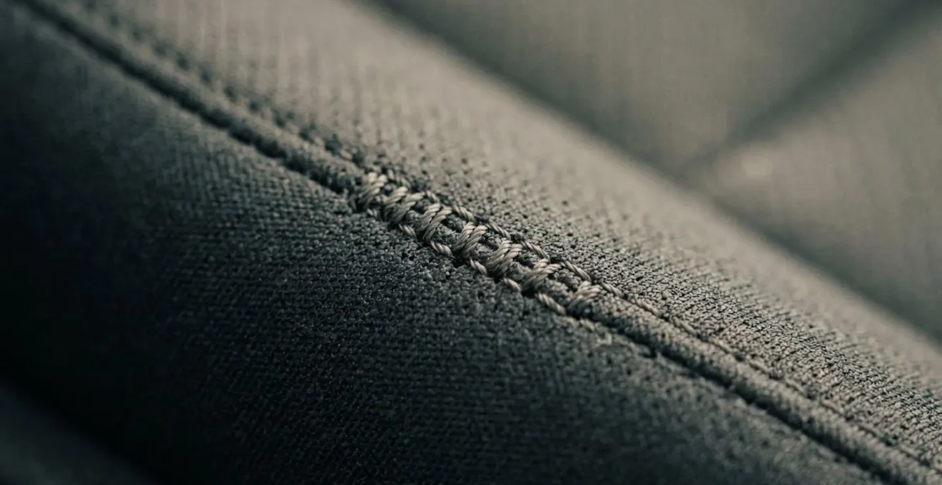 Gros plan sur la couture spéciale d'une housse de siège certifiée compatible airbag montrant le fil technique à point de rupture contrôlé