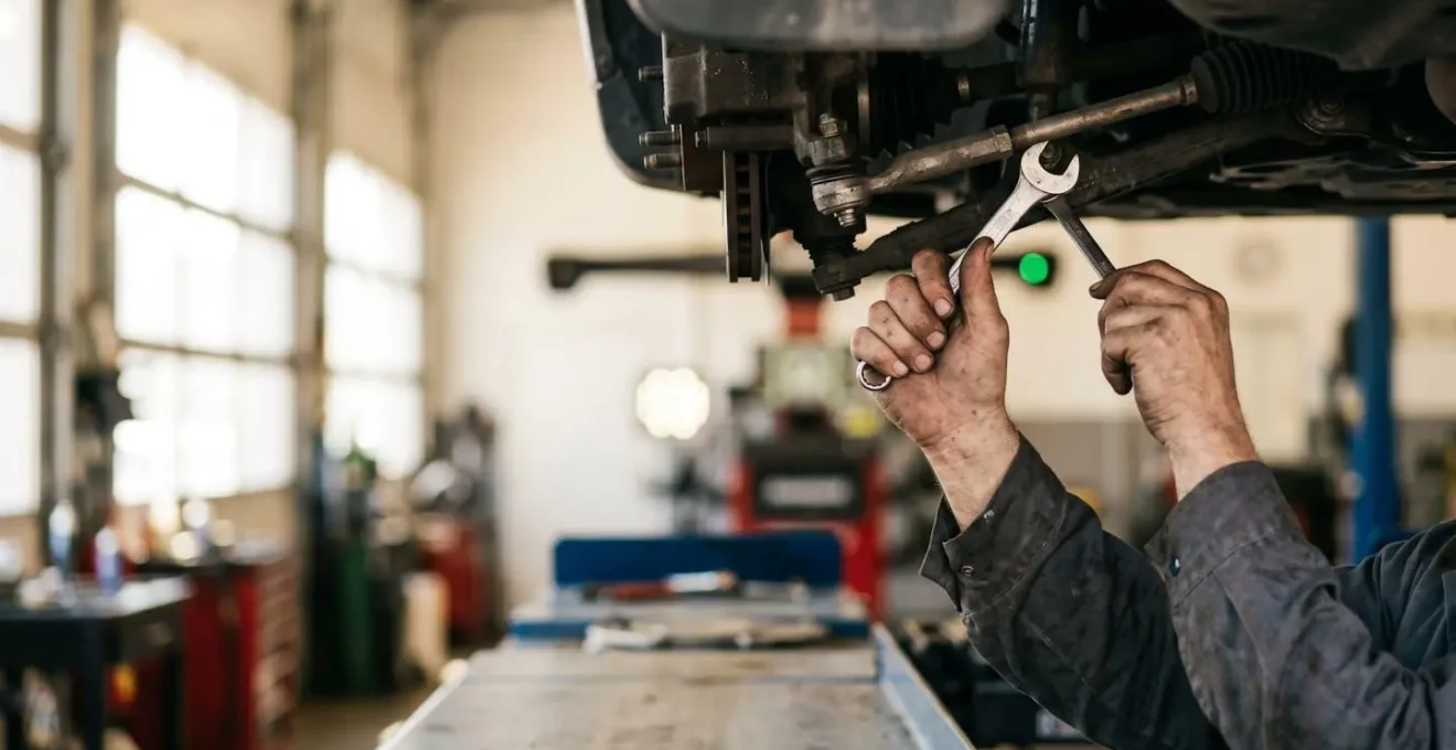 Mécanicien effectuant un réglage de géométrie sur un banc laser professionnel dans un atelier automobile