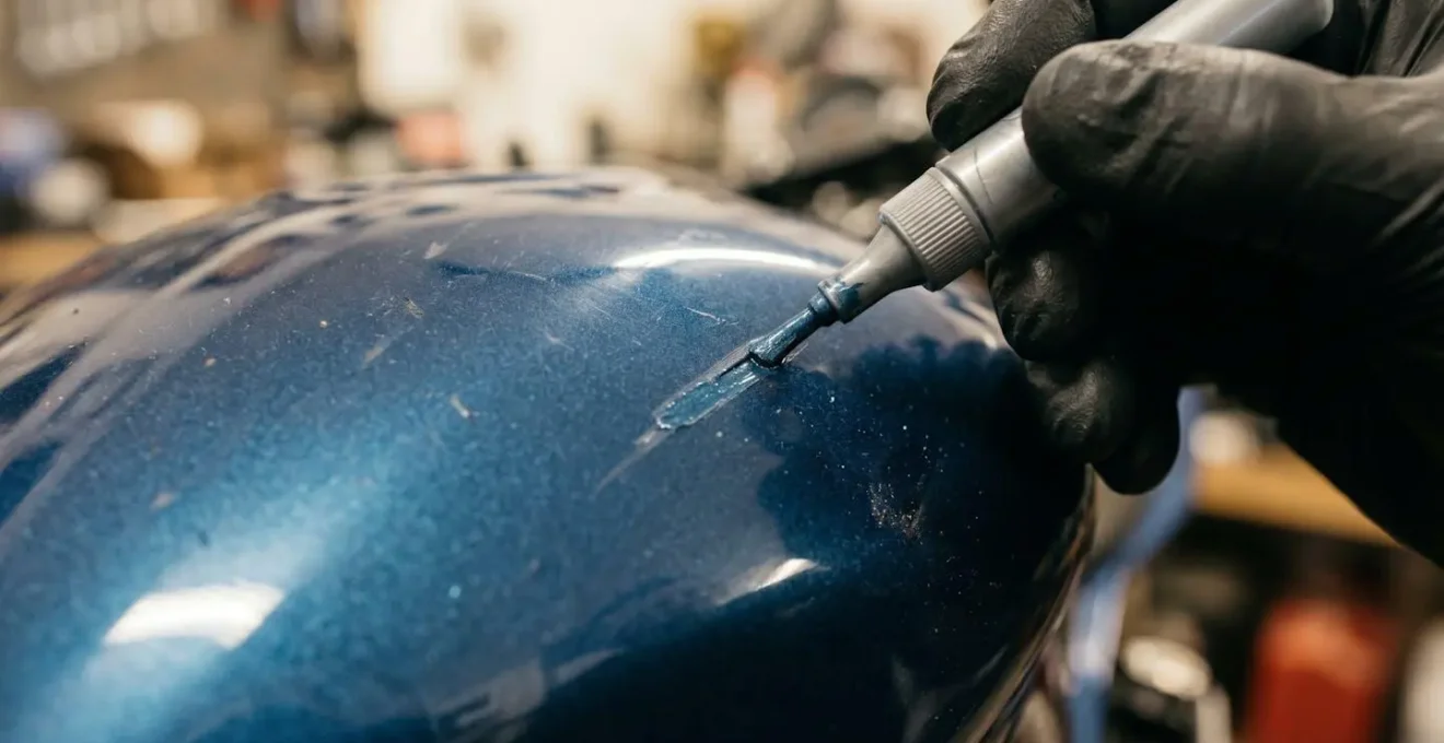 Gros plan sur une rayure de carénage moto en cours de réparation avec un stylo retouche
