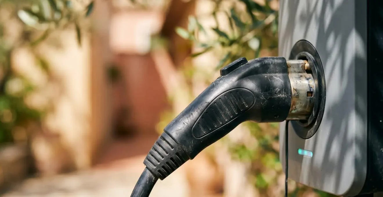 Gros plan sur un câble de recharge pour voiture électrique branché à une borne privée dans un environnement hôtelier méditerranéen